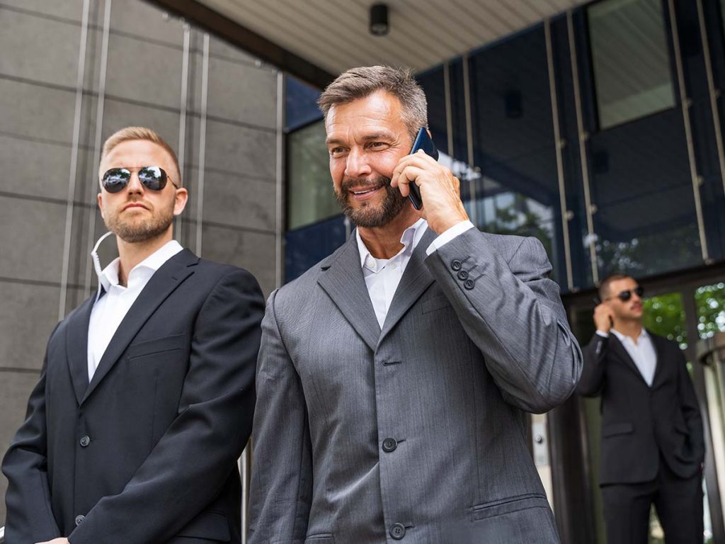 Security deatil with businessman on phone