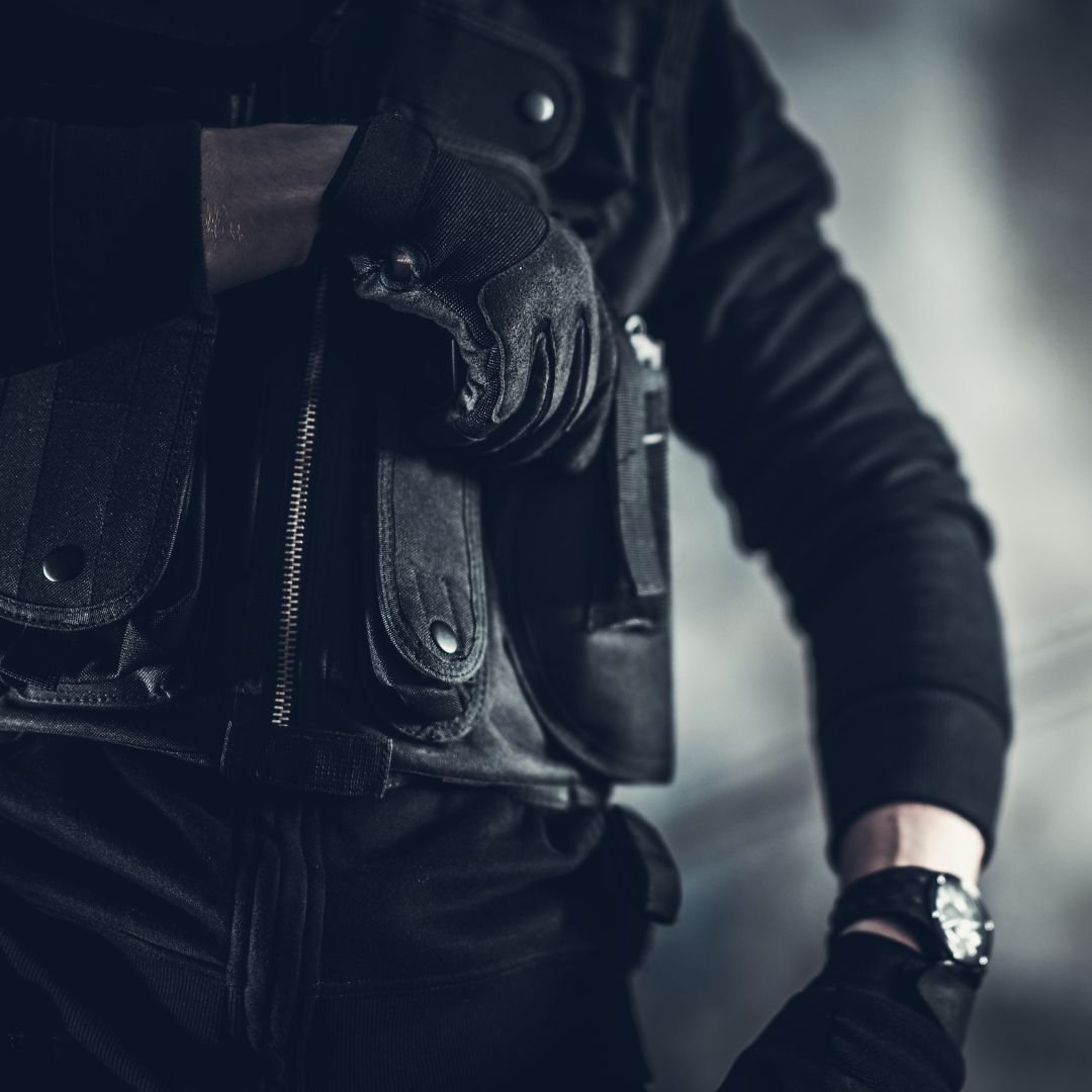 Individual wearing tactical gear reaching for a holstered gun