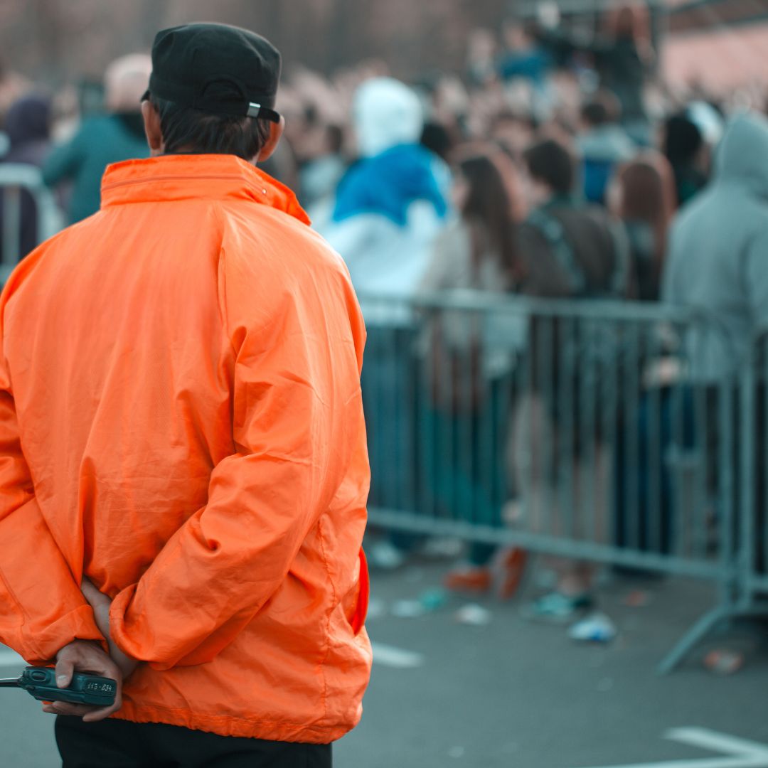 a security guard at an event in an orange jacket